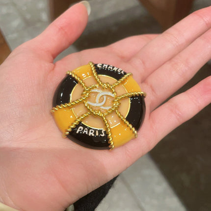 CHANEL 26S DOUBLE C LOGO PARIS ROUND ENAMEL BROOCH IN BLACK & AMBER WITH ROPE DETAIL GOLD METAL 629194
